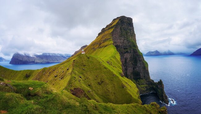 Kleiner Leuchtturm in der Nähe riesiger Klippen auf der Insel Kalsoy, FäröerInseln