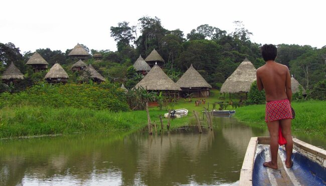 Embera auf einem Boot vor dem Dorf