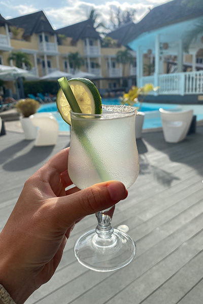 Hand mit Cocktailglas am Hotelpool