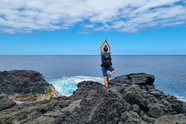 Wanderin in Yogapose vor Meer auf La Réunion